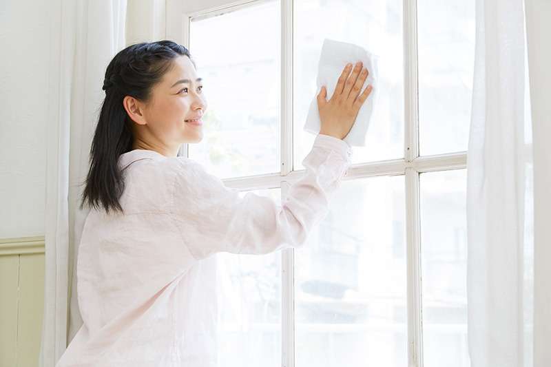 窓をクリーニングする女性